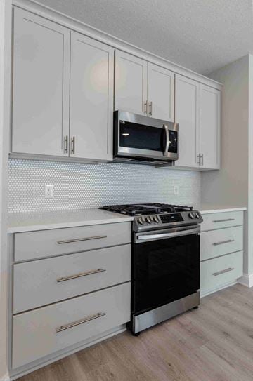Woodbury house for rent - a kitchen with white cabinets and a stove and microwave