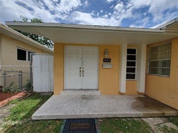 Miami apartment for rent - A yellow house with a white door and a small porch.