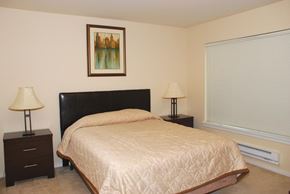 Renton apartment for rent - A bedroom with a bed, two lamps, and a picture on the wall.