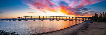 Coronado apartment for rent - A beautiful sunset view of a bridge over a calm body of water with boats docked underneath.