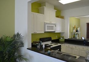 Newport News apartment for rent - Opening with Black Countertops From Living Room Into Kitchen with White Cabinets, Standard Appliances and an Opening Through to Dining Room