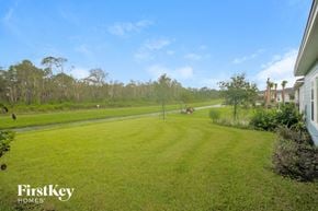Palm Coast house for rent - a view of the backyard of a house with a field of grass and a road