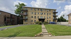Cincinnati apartment for rent - A large apartment building with a blue car parked in front.