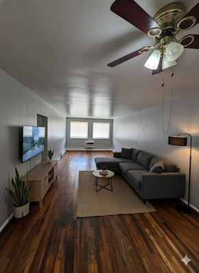 Cincinnati apartment for rent - A living room with a grey couch, a coffee table, a television, and a ceiling fan.