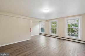 Coatesville apartment for rent - A spacious room with wooden flooring and two windows.