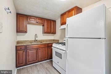 Coatesville apartment for rent - A kitchen with a white fridge, stove and wooden cabinets.