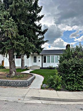 Calgary house for rent - A white house with a tree in front of it.