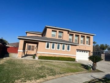 Tulare house for rent - a large brick house with a garage and a lawn