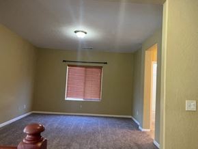 Tulare house for rent - an empty room with a window and a carpeted floor