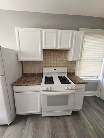 Cincinatti apartment for rent - A white kitchen with a stove top oven and a refrigerator.