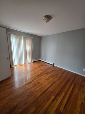 Cincinnati apartment for rent - A room with wooden floors and a window with curtains.