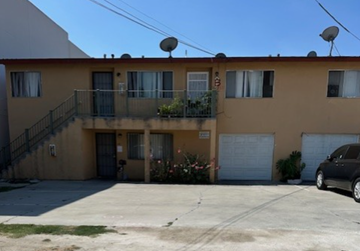 Paramount multi-family for rent - A two-story apartment building with a balcony on the second floor.