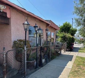 Commerce apartment for rent - A pink building with a metal fence and lamp posts.