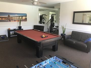 Huntington Beach apartment for rent - a red pool table in a living room with a black couch