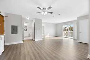 Naperville apartment for rent - A spacious room with a ceiling fan and light fixture, and a wooden floor.