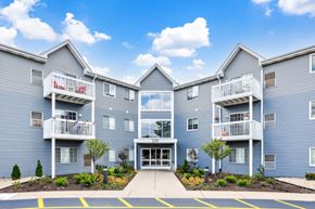 Naperville apartment for rent - A large blue building with a white balcony and a red sign that says "Apartments".