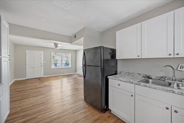 Roswell apartment for rent - A kitchen with a black refrigerator and white cabinets.