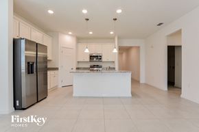 Kissimmee house for rent - a white kitchen with a large island and stainless steel refrigerator