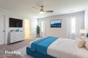 Greenville house for rent - A bedroom with a blue and white bed, a ceiling fan, and a painting on the wall.