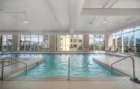Port Moody apartment for rent - A large indoor swimming pool with a tiled floor and a glass wall.