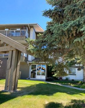 Hinton apartment for rent - A large white house with a balcony and a tree in front.