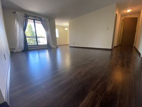 Hinton apartment for rent - A room with wooden floors and a large window with curtains.