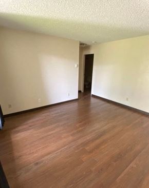 Hinton apartment for rent - A room with wooden flooring and a door in the background.