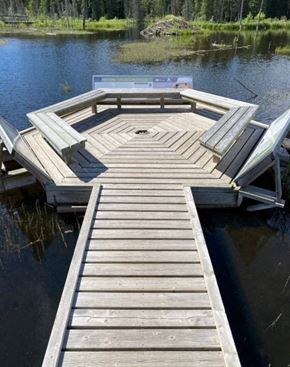 Hinton apartment for rent - A wooden dock extends into a lake with a boat tied to it.