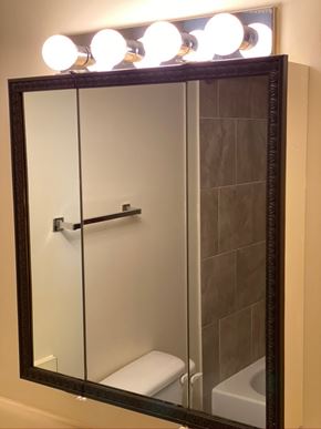 Hinton apartment for rent - A mirror with lights on top reflects a bathroom with a toilet and a shower.