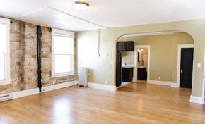 Fargo apartment for rent - an empty living room with a wood floor and a brick wall