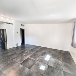 Palm Desert apartment for rent - an empty living room with white walls and a stainless steel refrigerator