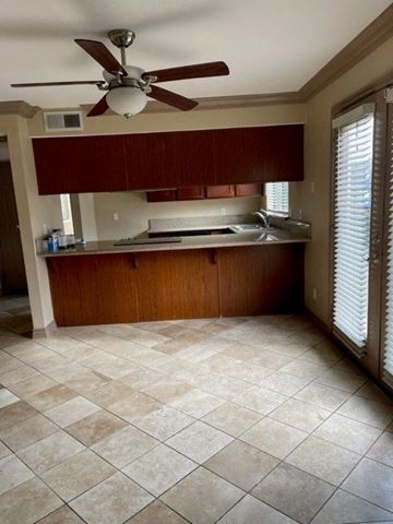 Fresno apartment for rent - A kitchen with a fan on the ceiling and a sink in the middle.