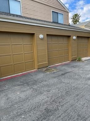 Fresno apartment for rent - Two garage doors are closed and there is a small plant to the right of the garage doors.