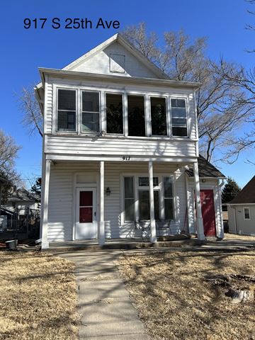 Omaha apartment for rent - A white two-story house with a red door and windows is located at 917 S 25th Ave.