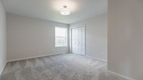 Hugo house for rent - A room with a carpeted floor and a window with a white door.