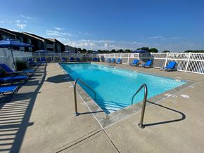 Speedway apartment for rent - A large swimming pool with a metal ladder and blue lounge chairs.