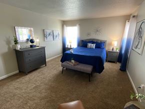 Speedway apartment for rent - A bedroom with a blue bed and a brown chair.