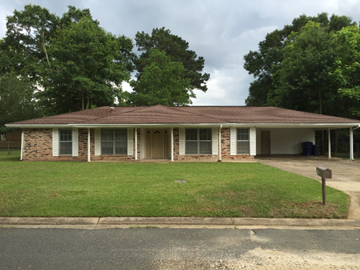Deridder house for rent - the front of a brick house with a lawn and trees