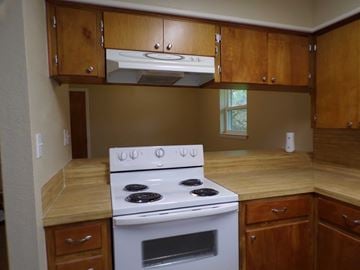 Buchanan Dam apartment for rent - A white stove with four burners is in a kitchen with wooden cabinets.