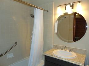 Burnet apartment for rent - A bathroom with a white shower curtain and a round mirror above a sink.