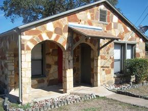 Austin apartment for rent - A house with a red door and a stone wall.