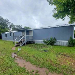Marble Falls apartment for rent - A blue building with a metal roof and a small tree in front of it.
