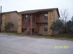 Marble Falls apartment for rent - A brown building with a balcony and a bicycle parked in front.