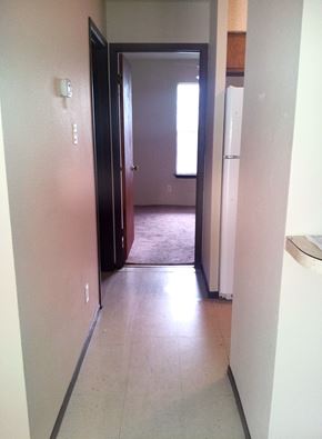 Marble Falls apartment for rent - A hallway with a door on the left and a refrigerator on the right.