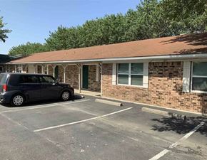Burnet apartment for rent - an empty parking lot in front of a brick building with a car parked