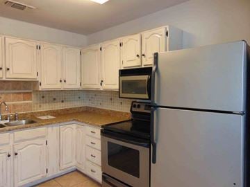 Granite Shoals apartment for rent - A kitchen with white cabinets and a black stove top oven.