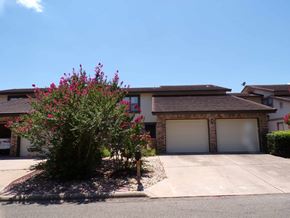 Marble Falls apartment for rent - A house with a brown roof and a tree with pink flowers in front.
