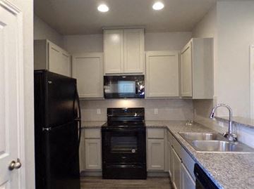 Marble Falls apartment for rent - a kitchen with black appliances and white cabinets