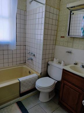 Gary house for rent - A white toilet sits next to a yellow bathtub in a bathroom.