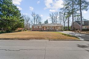 Jacksonville house for rent - A house with a brown roof and white windows is surrounded by trees and grass.